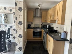 una piccola cucina con armadi in legno e lavandino di 2 bedroom house close to city centre with gated driveway a Liverpool