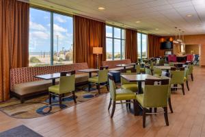 uma sala de jantar com mesas, cadeiras e janelas em Hampton Inn Virginia Beach-Oceanfront South em Virginia Beach