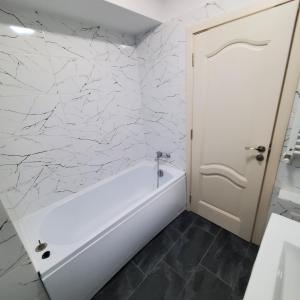 a bathroom with a white tub and marble walls at Luxury Apartament Bacovia in Bacău +32 photos