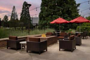 un patio avec des chaises et un foyer extérieur avec des parasols dans l'établissement TownePlace by Marriott Suites Portland Vancouver, à Evergreen