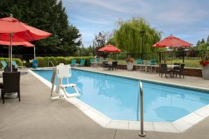 une grande piscine avec des chaises et des parasols dans l'établissement TownePlace by Marriott Suites Portland Vancouver, à Evergreen
