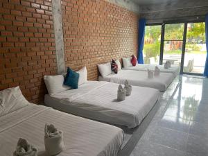 4 camas alineadas contra una pared de ladrillo en Irak Resort Ao Manao , en Klong Wan