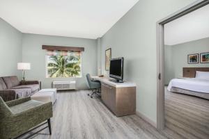 Cette chambre comprend un lit et un bureau avec une télévision. dans l'établissement Hilton Garden Inn Palm Beach Gardens, à Palm Beach Gardens