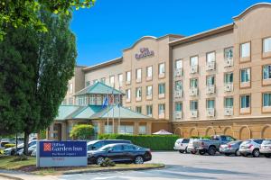 een hotelgebouw met auto's geparkeerd op een parkeerplaats bij Hilton Garden Inn Portland Airport in Portland