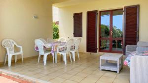 una camera con tavolo e sedie su un patio di Villetta Turagri 22 a soli 300 m dalla spiaggia 10 posti letto a Costa Rei
