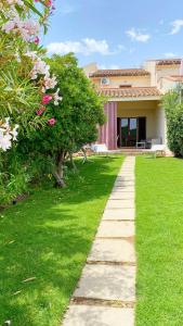 un giardino con passerella di fronte a una casa di Villetta Turagri 22 a soli 300 m dalla spiaggia 10 posti letto a Costa Rei