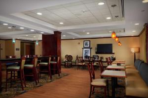 a restaurant with a bar and tables and chairs at Hampton Inn Newport News-Yorktown in Newport News