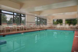 a large swimming pool with chairs and tables and windows at Hampton Inn Newport News-Yorktown in Newport News