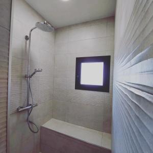 a bathroom with a shower with a tv on the wall at B&B Sara Sueño in Málaga