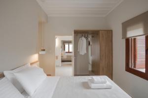 1 dormitorio con cama blanca y espejo en Villa Methexis en Arménoi