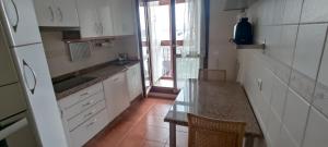 a kitchen with white cabinets and a glass table at Apartamento Laguna in Ribadeo
