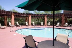 a swimming pool with a table and an umbrella at Hilton Garden Inn Phoenix Airport in Phoenix