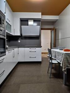 una cocina con armarios blancos y una mesa con sillas. en Casa Nicolas, en Chantada