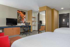 a hotel room with two beds and a desk with a television at Hilton Garden Inn Phoenix Airport in Phoenix