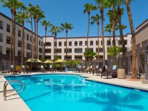 una imagen de una piscina en un hotel con palmeras en Hilton Phoenix Airport en Phoenix