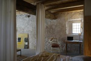 a bedroom with a bed and a desk and a window at CAN TAT, Loft in a old coach house in Sant Jordi Desvalls