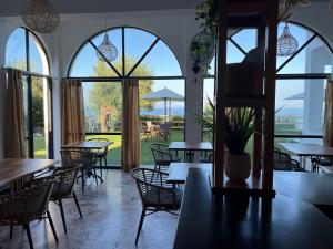 a restaurant with tables and chairs and large windows at Nikoli Apartments in Benitses
