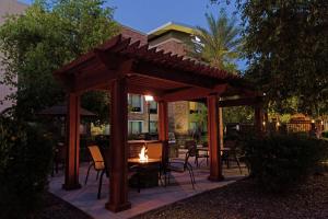 a wooden pergola with chairs and a table with a fire at Homewood Suites by Hilton Phoenix Chandler Fashion Center in Chandler