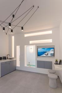 a white kitchen with a flat screen tv on the wall at Linea Luxury Suites in Fira