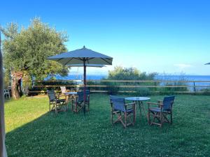 a table and chairs with an umbrella in the grass at Nikoli Apartments in Benitses