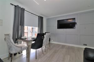 2 Bedroom Apartment at SECC Hydro FREE PARKING في غلاسكو: غرفة طعام مع طاولة وكراسي وتلفزيون