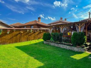 a house with a fence and a green yard at Златкова къща in Koprivshtitsa