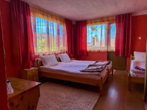 a bedroom with a bed with red walls and windows at Златкова къща in Koprivshtitsa