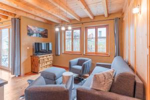 a living room with a couch and two chairs and a tv at Eco Chalet Olival in Braies