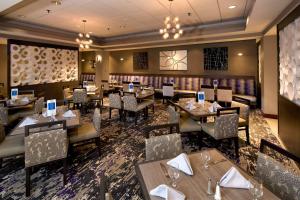 ポートランドにあるEmbassy Suites by Hilton Portland Maineのテーブルと椅子が備わるレストラン