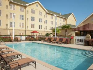 un hotel con piscina con sillas y un hotel en Homewood Suites by Hilton Pensacola Airport-Cordova Mall Area en Pensacola