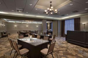 Embassy Suites by Hilton Portland Maine في بورتلاند: قاعة اجتماعات مع طاولات وكراسي وثريا