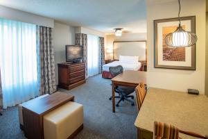 um quarto de hotel com um quarto com uma cama e uma secretária em Homewood Suites by Hilton Pensacola Airport-Cordova Mall Area em Pensacola