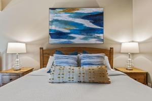 a bedroom with a bed with two lamps and a painting at Top Floor Wolf - Best Views With Pool and Hot tub in Canmore