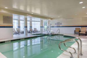 - une piscine avec des chaises et des tables dans un bâtiment dans l'établissement Hilton Garden Inn Portland Airport, à Portland