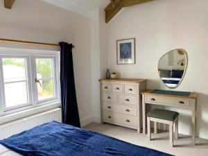 1 dormitorio con cama, tocador y espejo en Swallows Drift en Newquay