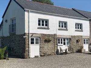 a white house with a stone building at Swallows Drift in Newquay