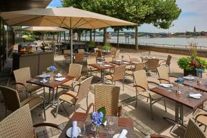 un restaurante al aire libre con mesas, sillas y un río en Hilton Mainz, en Mainz