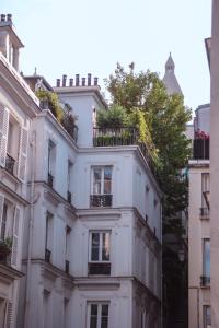 un edificio blanco con balcones y un árbol en Studio Montmartre, en París
