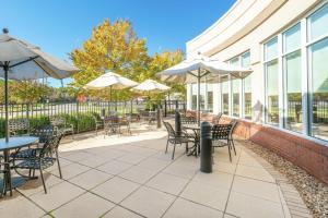 a patio with tables and chairs and umbrellas at Hilton Garden Inn Richmond Airport in Sandston