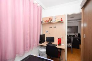 ein Büro mit rosa Vorhängen und einem Schreibtisch mit einem Computer in der Unterkunft Exotic Home Brazil in Belo Horizonte