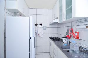 La cuisine blanche est équipée d'un évier et d'un réfrigérateur. dans l'établissement Exotic Home Brazil, à Belo Horizonte