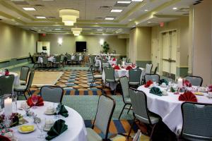 un salón de banquetes con mesas y sillas blancas en Hilton Garden Inn Richmond Airport en Sandston