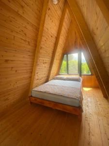 Ce lit se trouve dans une chambre en bois dotée d'une fenêtre. dans l'établissement Aşı garden bungalow evleri, à Ortaca
