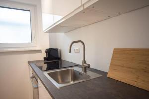 uma cozinha com um lavatório de aço inoxidável e uma janela em Central Apartment / BBQ Terrace / Big NetflixTV em Bayreuth