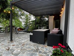 een pergola met een tafel en stoelen op een stenen patio bij Mountain Chalet - Cabana la Muntele Baisorii in Muntele Cacovei