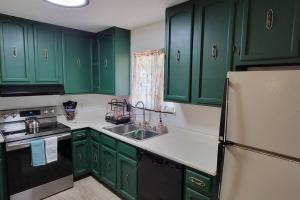 a green kitchen with green cabinets and a refrigerator at Casa Sunrise, Large Home, Minutes from Airport, YRMC, Mexico Borders in Yuma