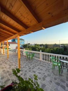 a patio with green chairs and tables and a wooden roof at Holiday House in Lezhë