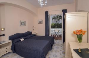 a bedroom with a blue bed and a vase of flowers at Le Querce Resort Sea Thermae & Spa in Ischia