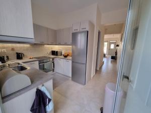 a kitchen with white cabinets and a stainless steel refrigerator at Eos House in Loutra