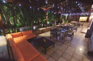 un patio al aire libre con sofá, mesas y sillas en Hilton Princess San Pedro Sula, en San Pedro Sula